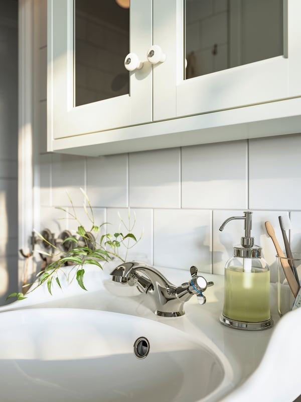 A close-up of a white TÄNNFORSEN mirror cabinet with doors over a sink with a HAMNSKÄR sink mixer tap.