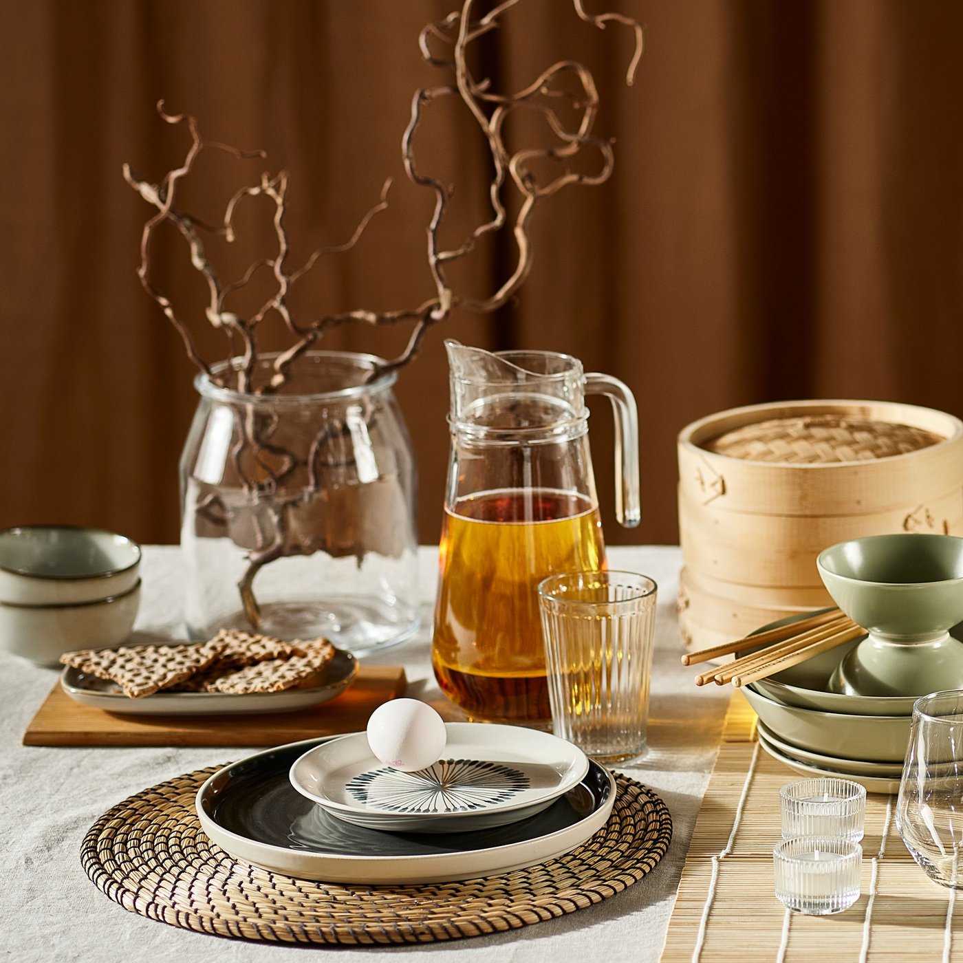 Ein gedeckter Tisch mit Wasserkrug, verschiedenen Tellern und anderer Auswahl an Geschirr und Tischsets aus der IKEA LÄTTAD Serie.