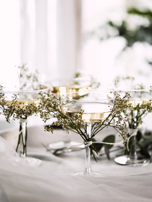 Quatre coupes à champagne STORHET sur un plateau et des brindilles de fleurs sauvages sont attachées aux pieds du verre.