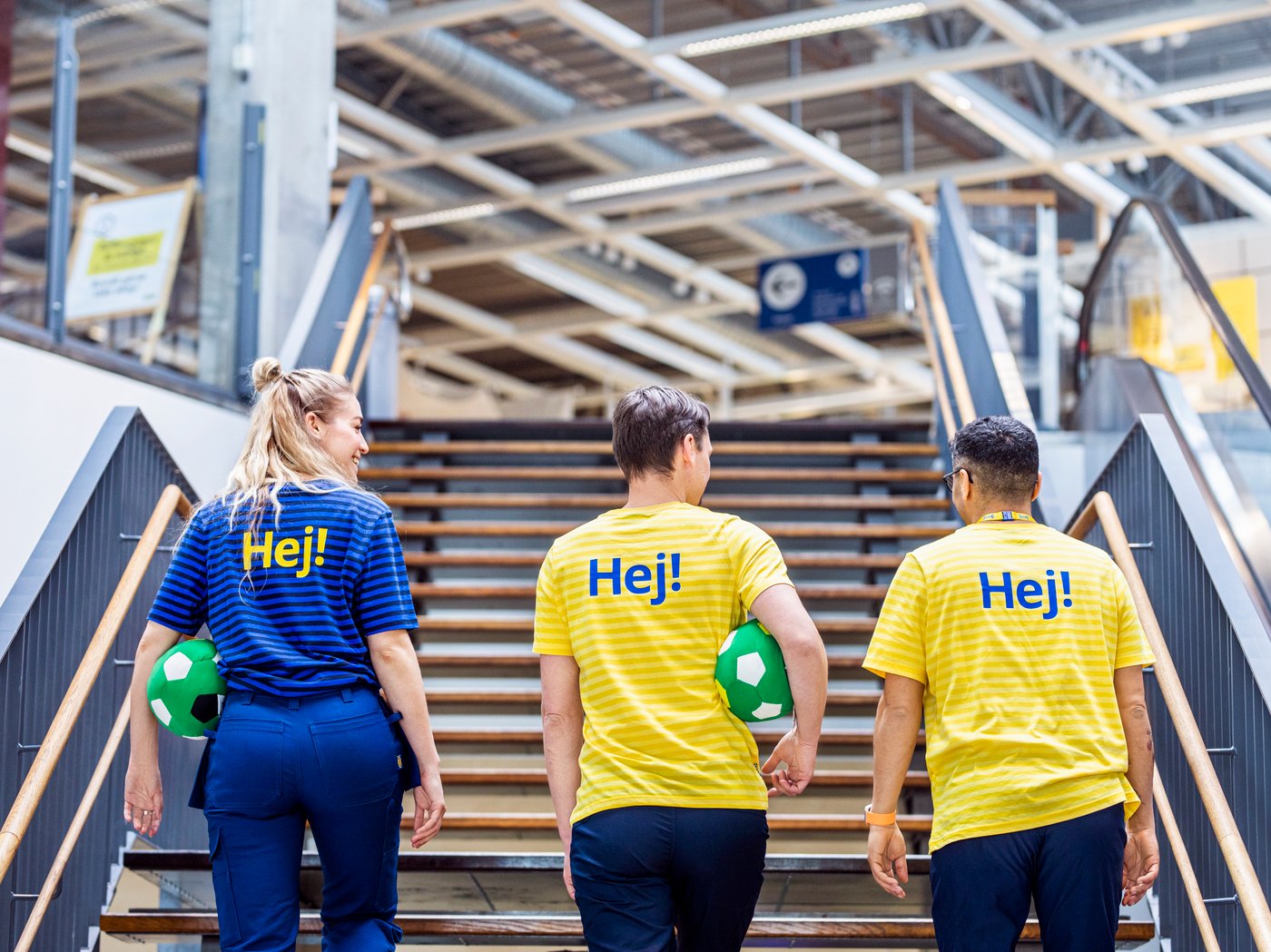 Tres colaboradores de IKEA subiendo la escalera principal de una tienda.