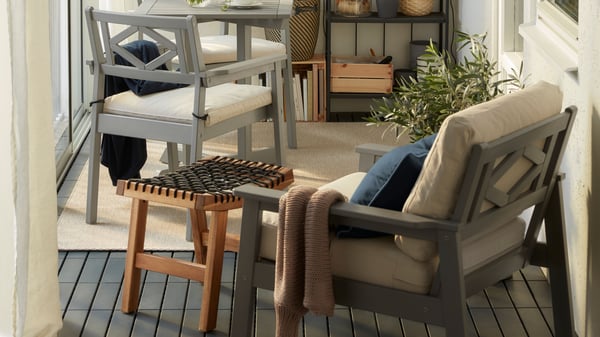 Überdachter Balkon mit grauer Sitzgruppe, weichen Polstern und Pflanzen – ideal für entspannte Stunden.

