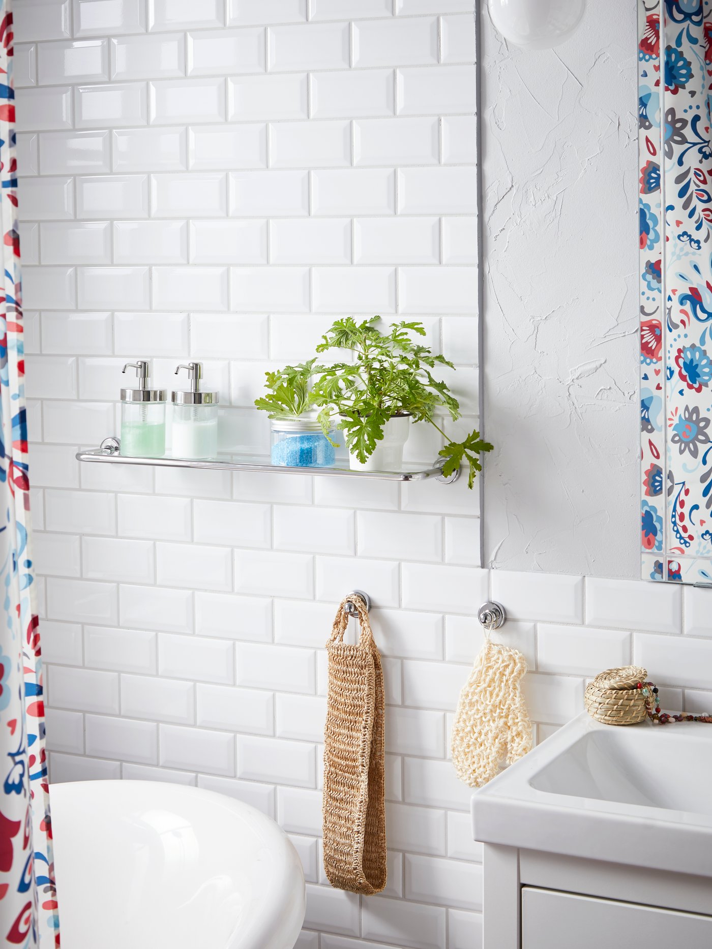 Para-para kaca VOXNAN dengan kesan krom diletakkan berdekatan tab mandi dan sink serta diletakkan sabun dan tumbuhan.