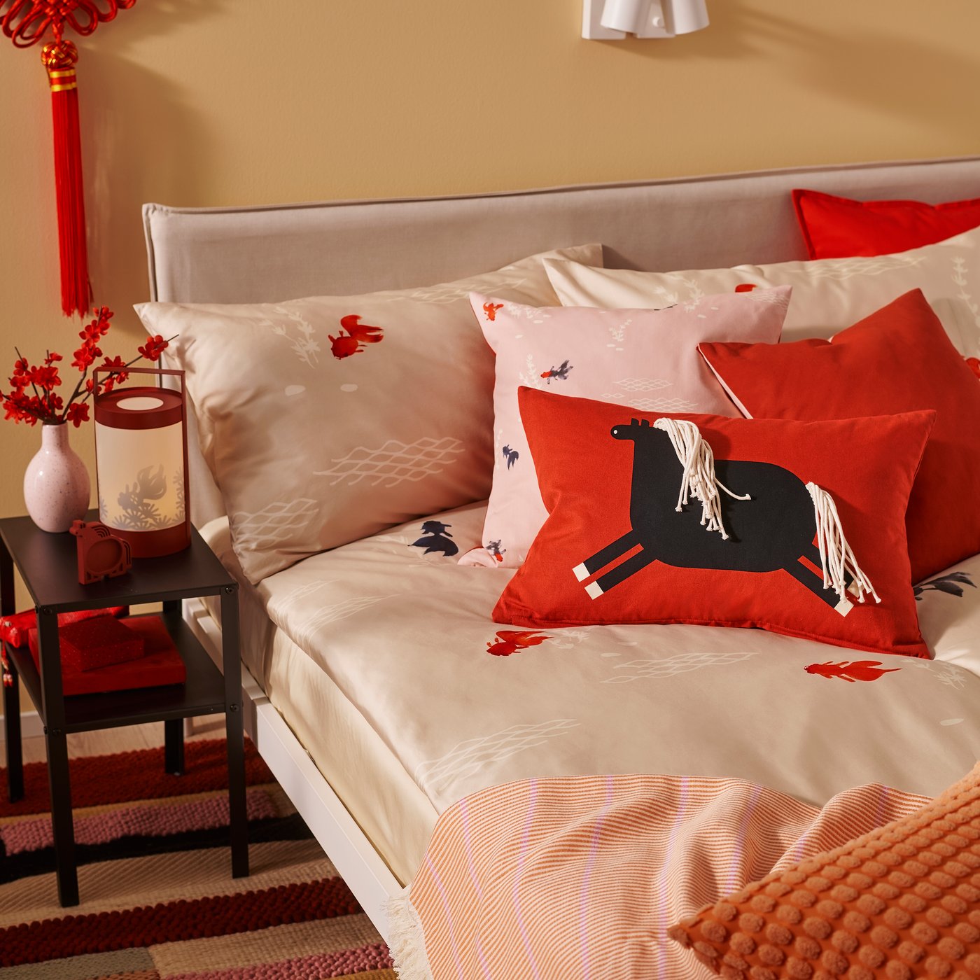 A red-orange VIGDIS cushion cover in the bedroom