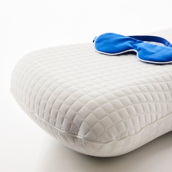 Close-up of a KLUBBSPORRE ergonomic cooling pillow. On top of it, a sleep mask.