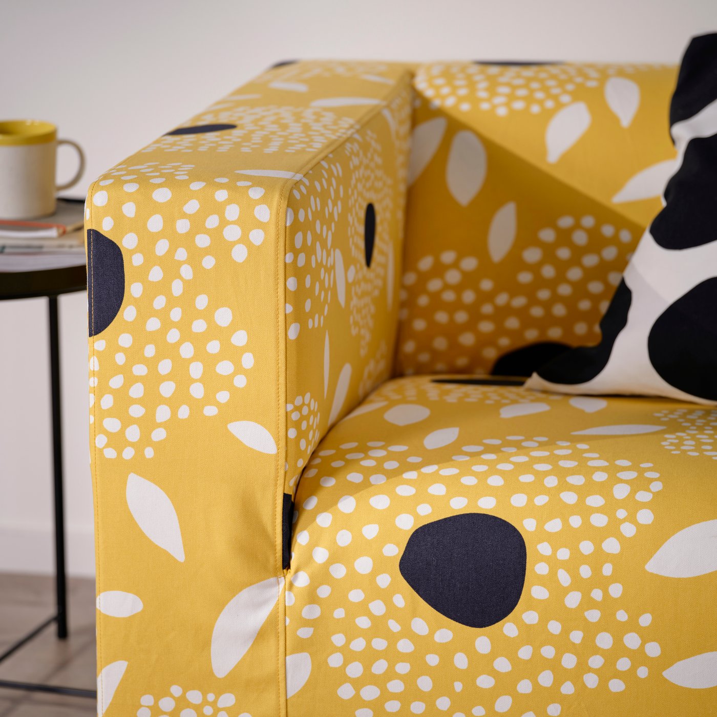 Dettaglio del rivestimento giallo, nero e bianco a motivi floreali per divano KLIPPAN.