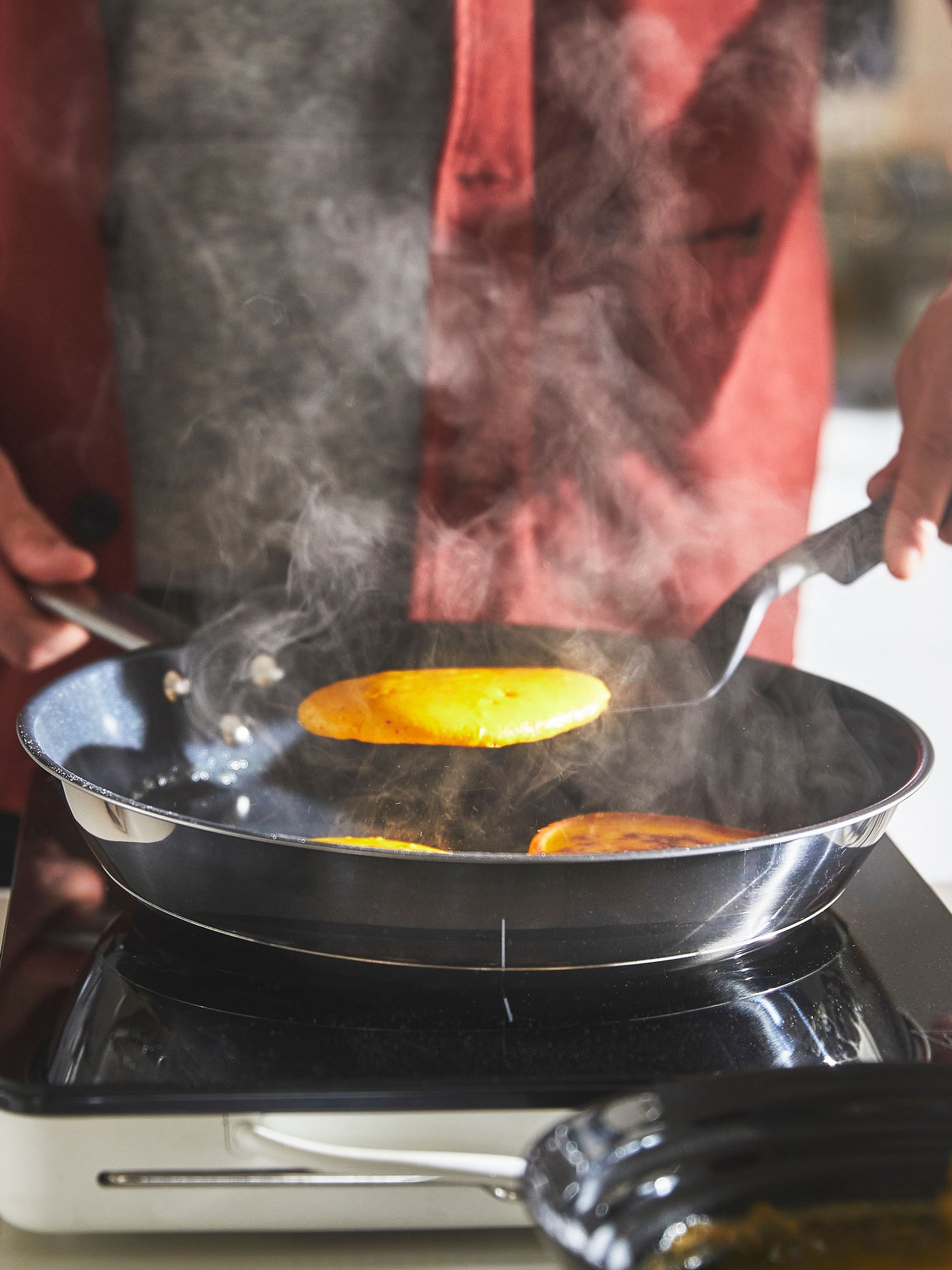 En IKEA 365+ stekepanne i rustfritt stål med slippbelegg på en TILLREDA bærbar induksjonstopp har et stekt egg i seg.