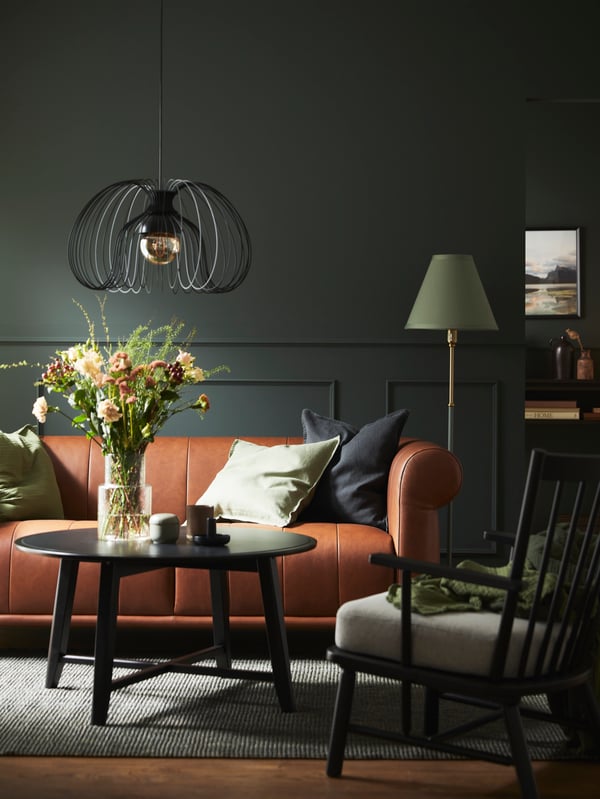 A KRAGSTA coffee table and a PERSBOL armchair stand in front of a leather VISKAFORS 2-seat sofa and a FLYGHÖJD floor lamp.