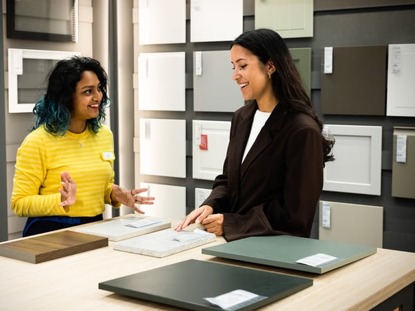 An IKEA employee helps a customer choose kitchen fronts.