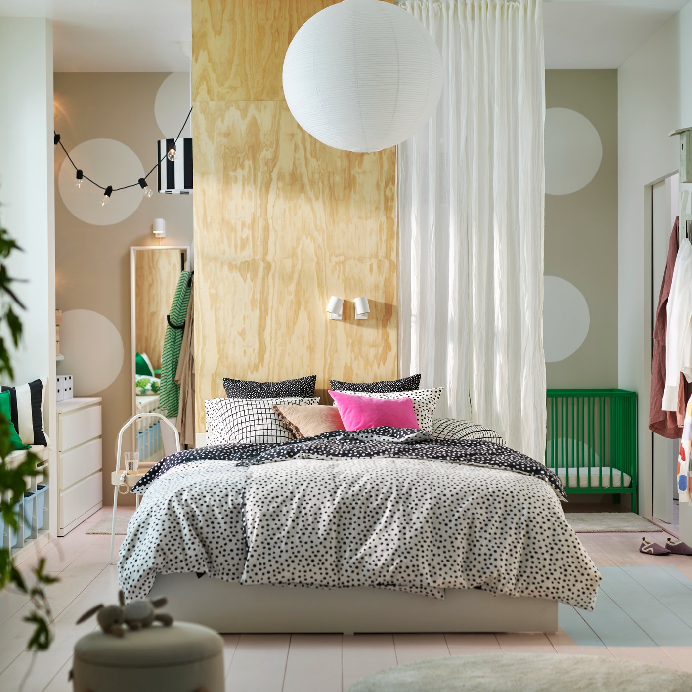 Un lit VIHALS avec quatre boîtes habillé de linge le lit BJÖRKGRÅMAL noir et blanc et de coussins aux couleurs vives dans une chambre lumineuse.