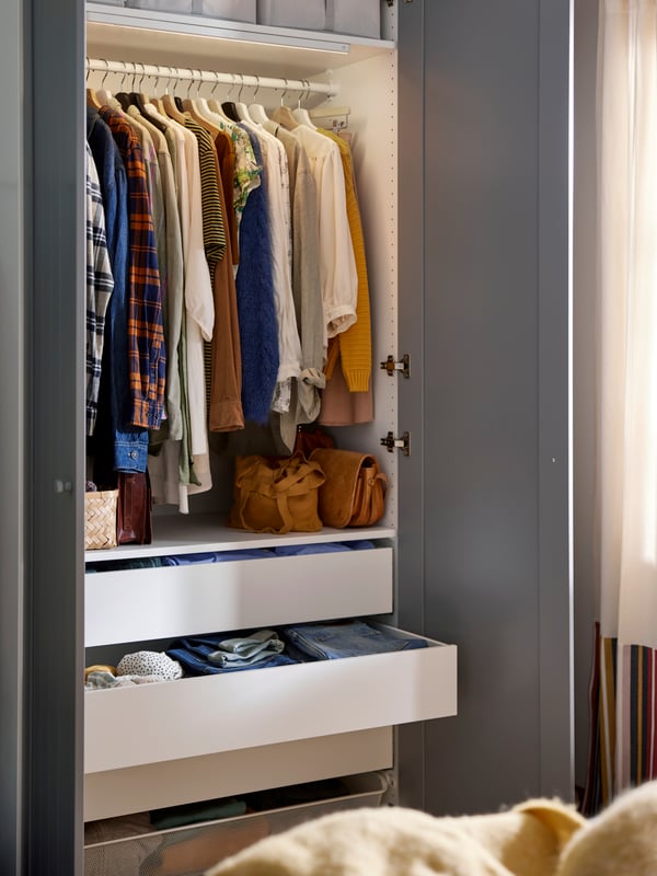 A dark grey/grey PAX/GULLABERG wardrobe combination with two doors open showing hanging clothes and storage boxes on shelves.