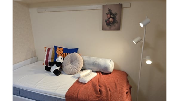 ベッドの上にパンダのぬいぐるみや、様々な色・形のクッションが置かれている。