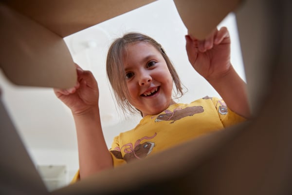 Young girl, excited, looking into paper bag.