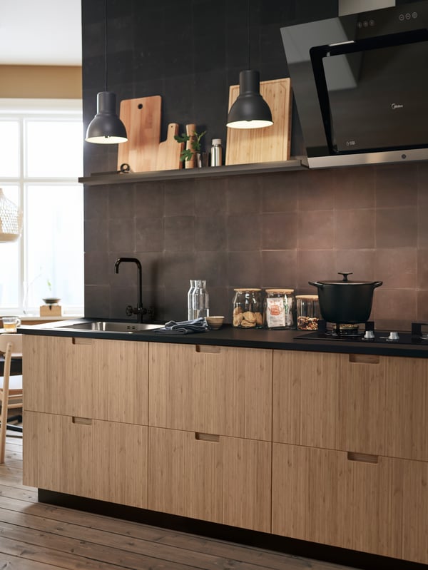 In this modern kitchen, FRÖJERED kitchen fronts in bamboo are paired with black tiled walls and accessories.