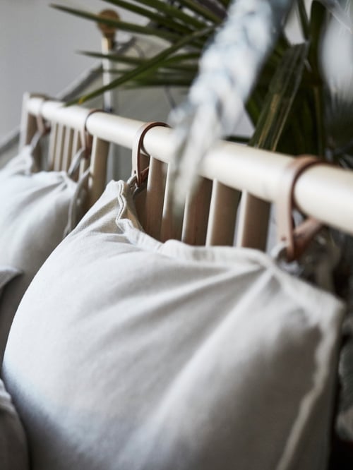 Gros plan de la tête de lit d’un cadre de lit BJÖRKSNÄS en bouleau, avec deux oreillers intégrés. Le lit est placé près d’un mur de plantes.