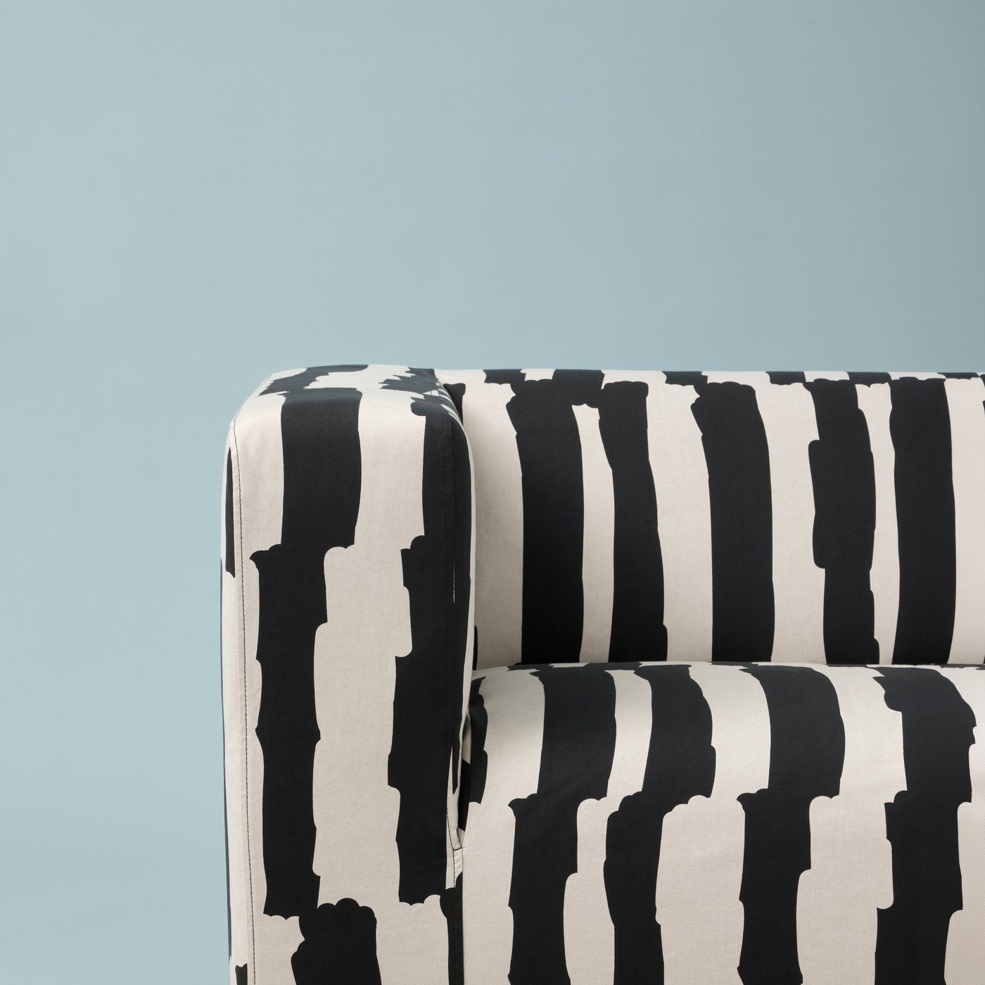 Part of a Grimsmåla black-and-white, zebra-stripe KLIPPAN two-seat sofa against a light-blue background.
