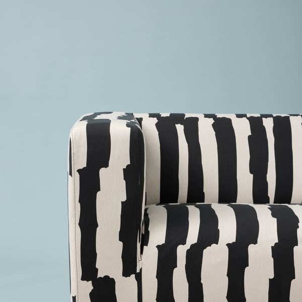 Part of a Grimsmåla black-and-white, zebra-stripe KLIPPAN two-seat sofa against a light-blue background.