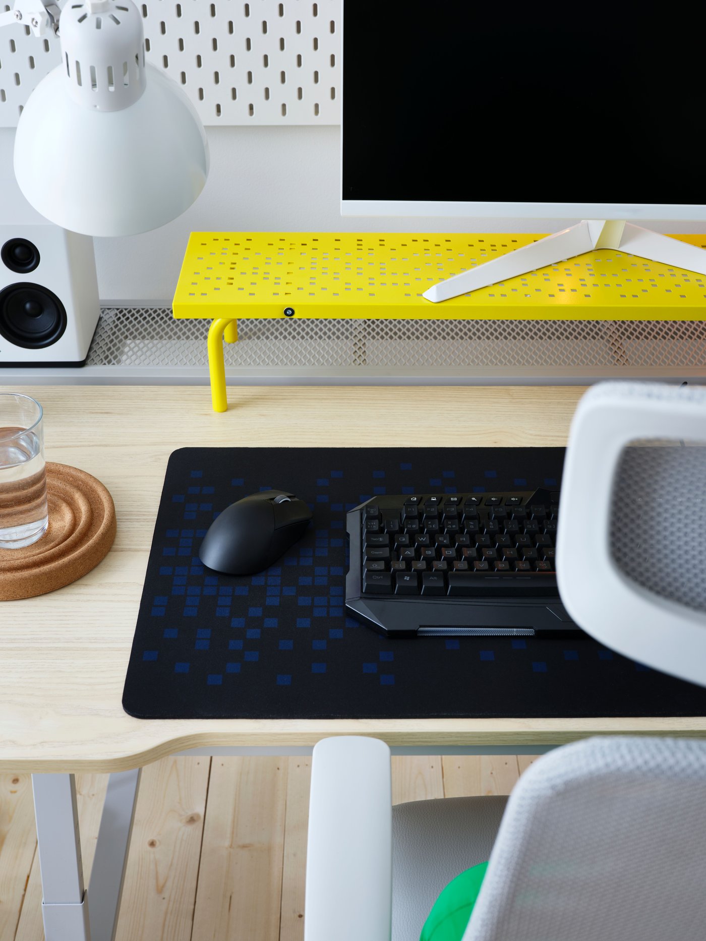 Sur un bureau de jeu vidéo à effet de frêne, support pour écran LÅNESPELARE jaune en acier perforé et tapis de souris de jeu BRÄNNBOLL.