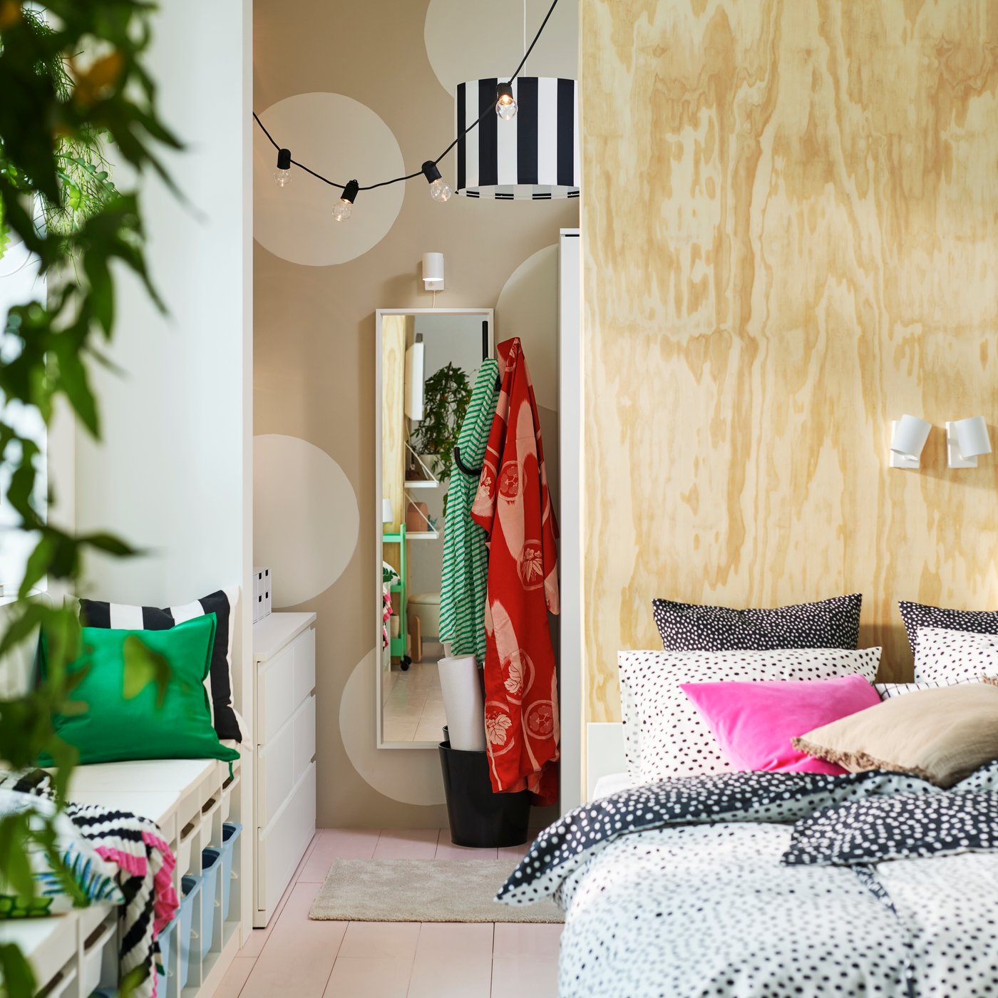 A VIHALS bed in front of a room divider that has a black ÄLGANÄS hat and coat stand and a white NISSEDAL mirror behind it.