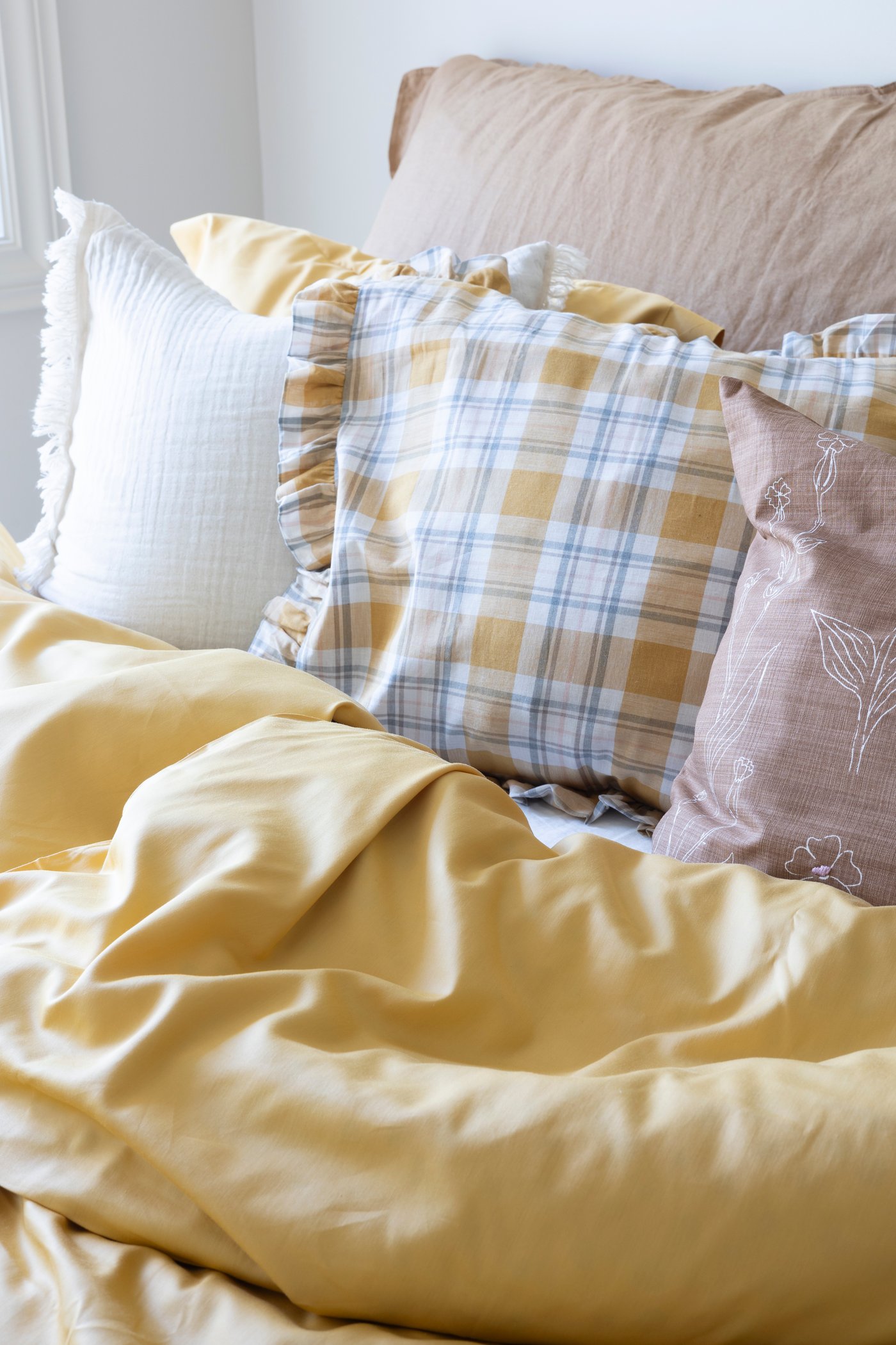 Ein gelber LUKTJASMIN Bettbezug und Kissenbezug auf einem Bett