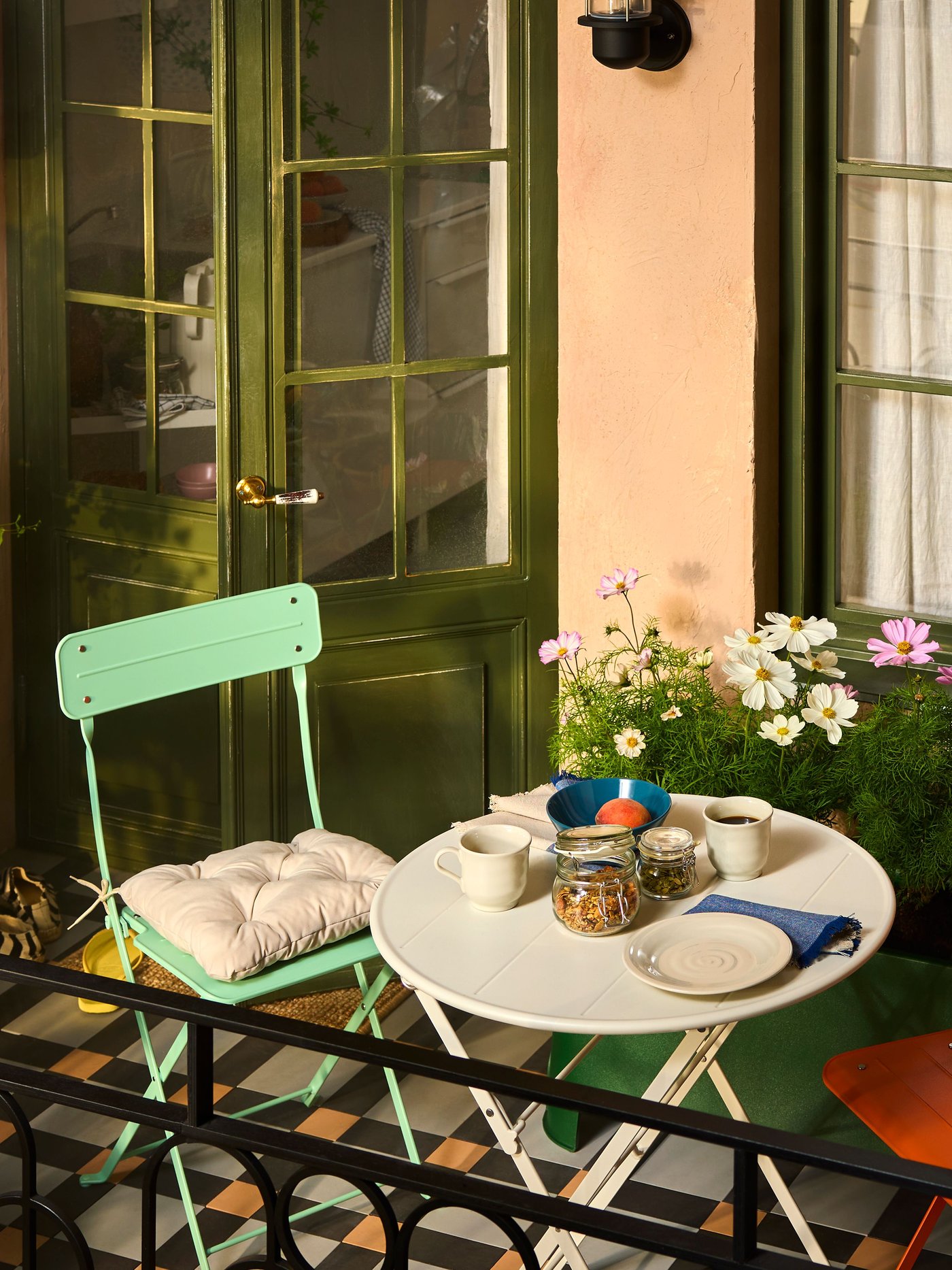 Balkong med SUNDSÖ utendørsmøbler i lekne farger omringet av planter, blomster og oppbevaring. 