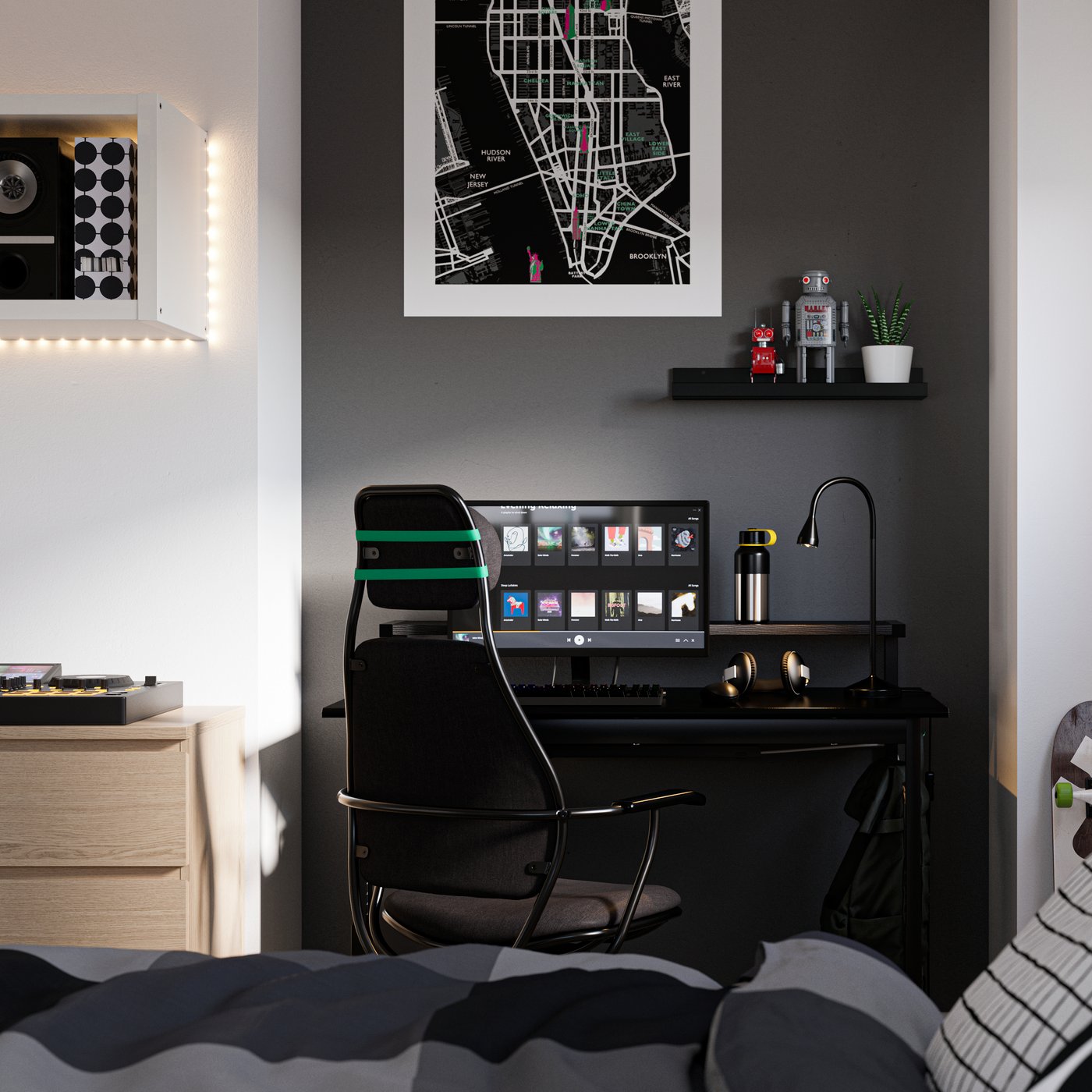 Bedroom with a bed in the foreground and a desk by a wall painted black in the back, with a computer and gaming chair.