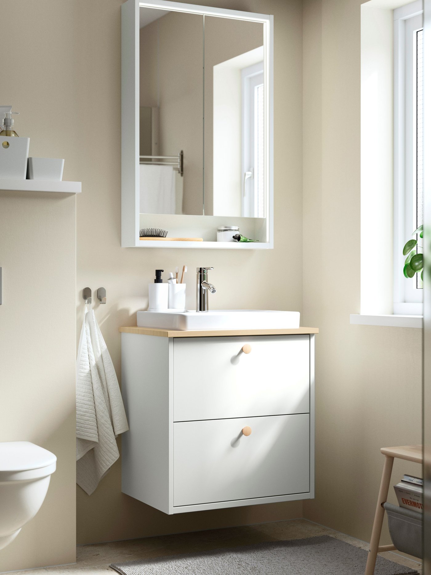 A bathroom with beige walls featuring a white HAVBÄCK wash-stand with drawers, an ORRSJÖN wash-basin and a mirror cabinet.