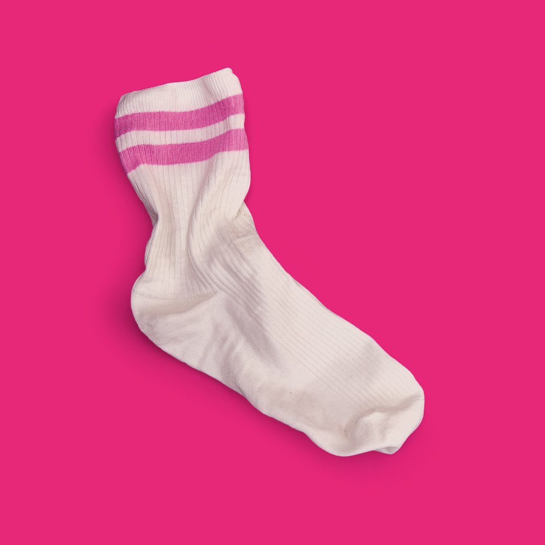Chaussette blanche avec deux bandes roses au niveau du bord, présentée sur un fond rose vif.