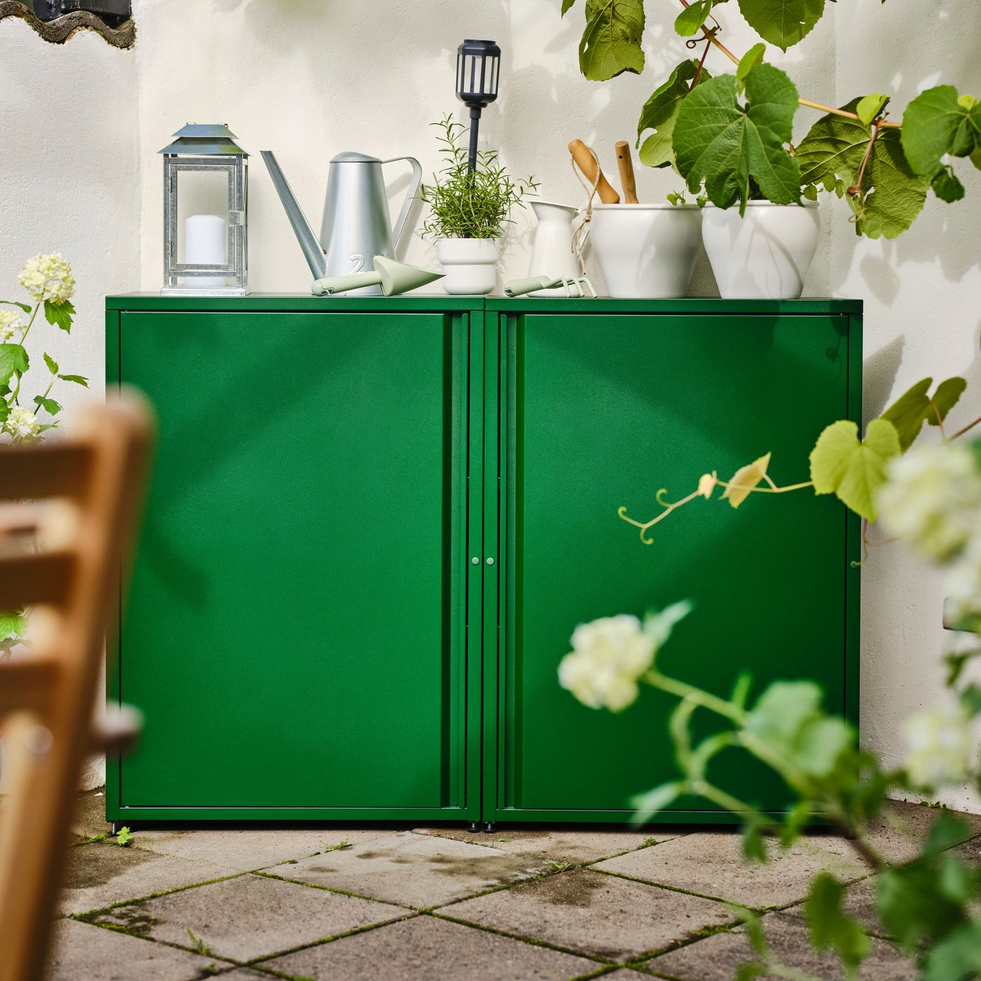 Dvě zelené skříňky SUNDSÖ postavené vedle sebe. Na nich je několik rostlin v květináčích a zahradnické náčiní.