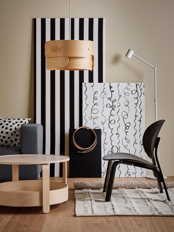 A black FRÖSET easy chair on a natural PEDERSBORG rug, next to a grey KLIPPAN sofa and a birch BORGEBY coffee table.