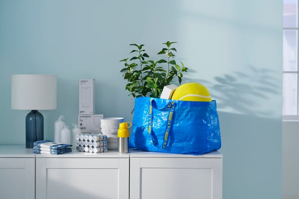Plusieurs articles IKEA et un sac bleu FRAKTA disposés sur un meuble blanc IKEA