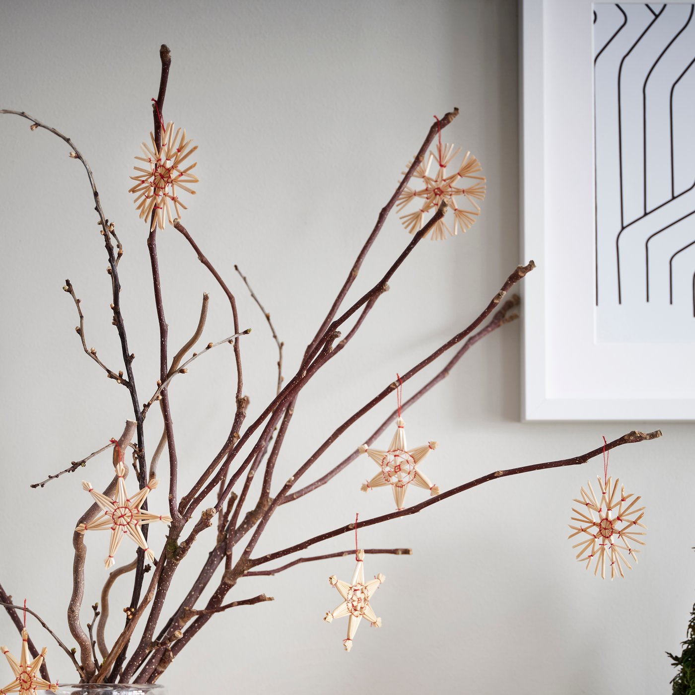 Håndlavede snefnug i forskellige former hænger på grene samlet i en vase.