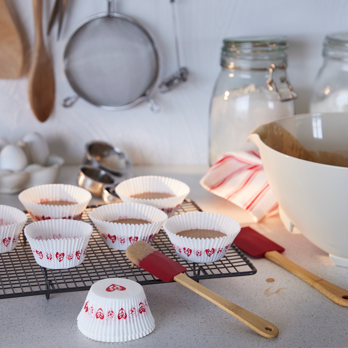 VINTERFINT 2022 baking cups with heart patterns are placed on a baking tray. VINTERFINT 2022 spatulas are placed beside the baking cups.