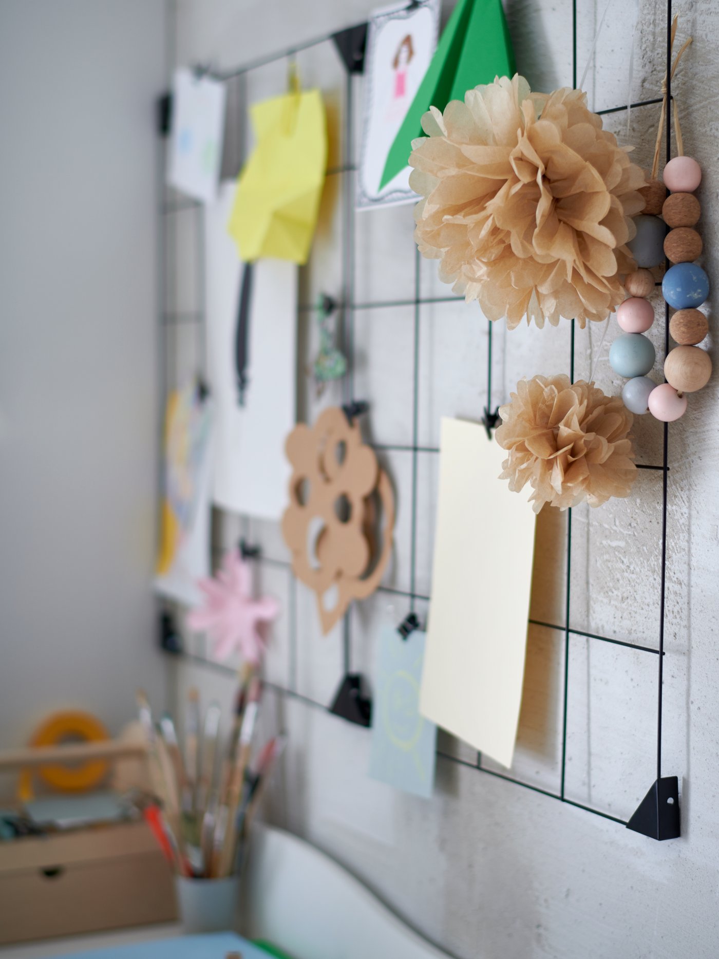 لوحة ملحوظات ‪SÖSDALA‬ سوداء مع مشابك على جدار أبيض، تتدلى منها رسومات وأعمال فنية وحرفية.