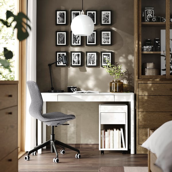 Ein weißer TONSTAD Schreibtisch mit Schublade und dem passenden TONSTAD Rollcontainer in einem Wohnzimmer. 
