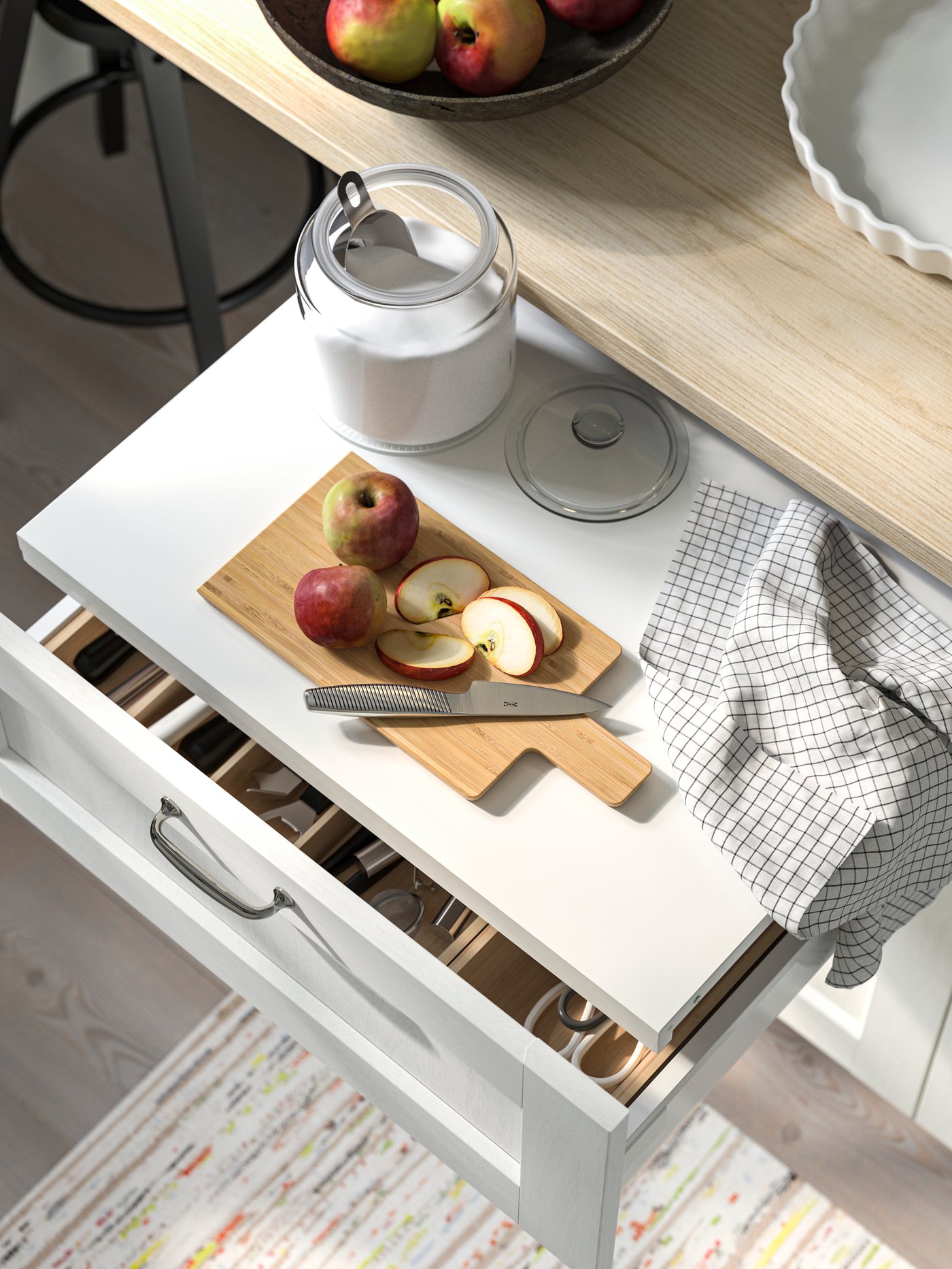 Cocina con una superficie de trabajo extráctil UTRUSTA blanca con una tabla de picar APTITLIG beige en la parte superior.