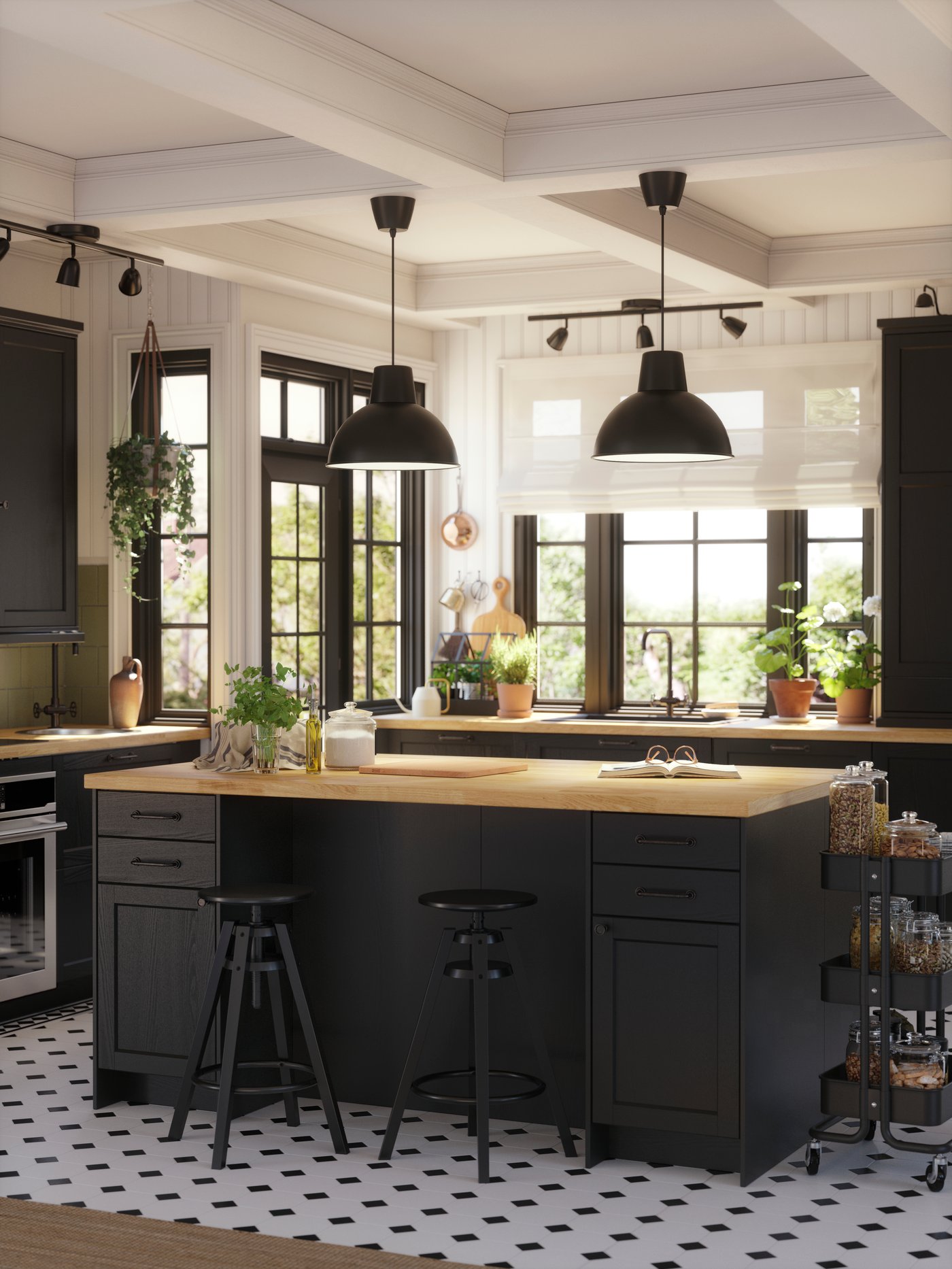 A big kitchen island with black-stained LERHYTTAN fronts and a wooden countertop has two big black pendant lamps above it.