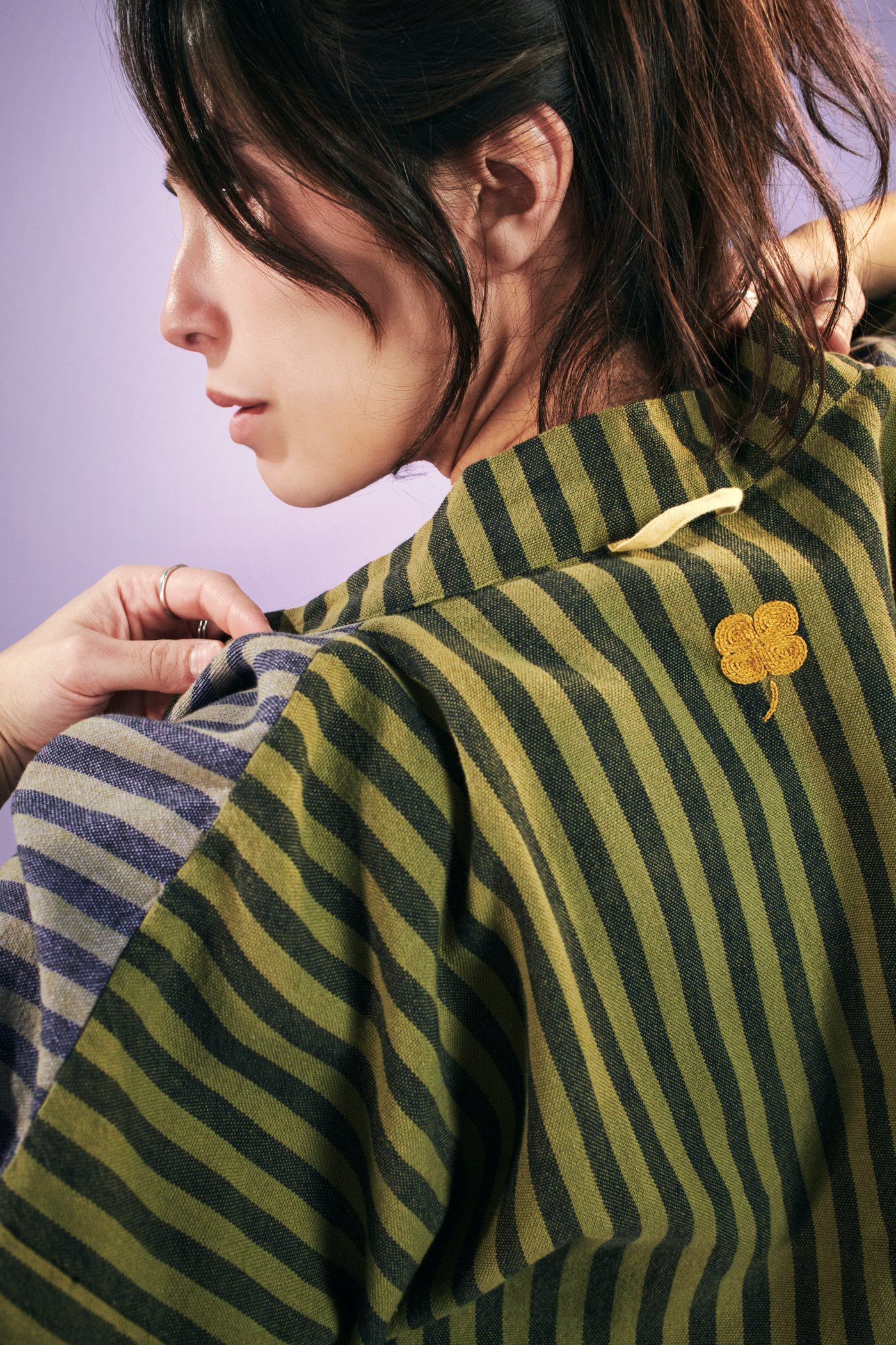 Perfil de una persona con una bata MÄVINN; se puede ver el trébol de cuatro hojas bordado a mano en la espalda.