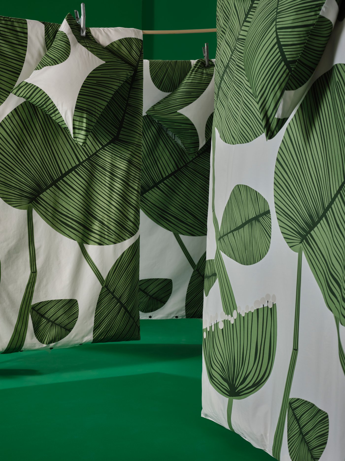 A display of bedding with the leafy-pattern, white-and-green KUNGSCISSUS duvet cover and pillowcase combination.