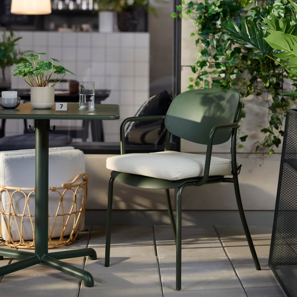 Café-Außenbereich mit tiefgrünen VISINGSÖ-Tischen und -Sesseln, umgeben von Grünpflanzen und Outdoor-Dekoration.