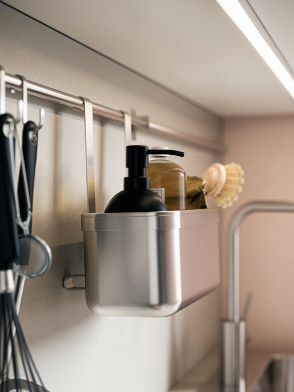 Stainless steel KUNGSFORS container with a soap dispenser and brush, mounted on a rail in a kitchen.