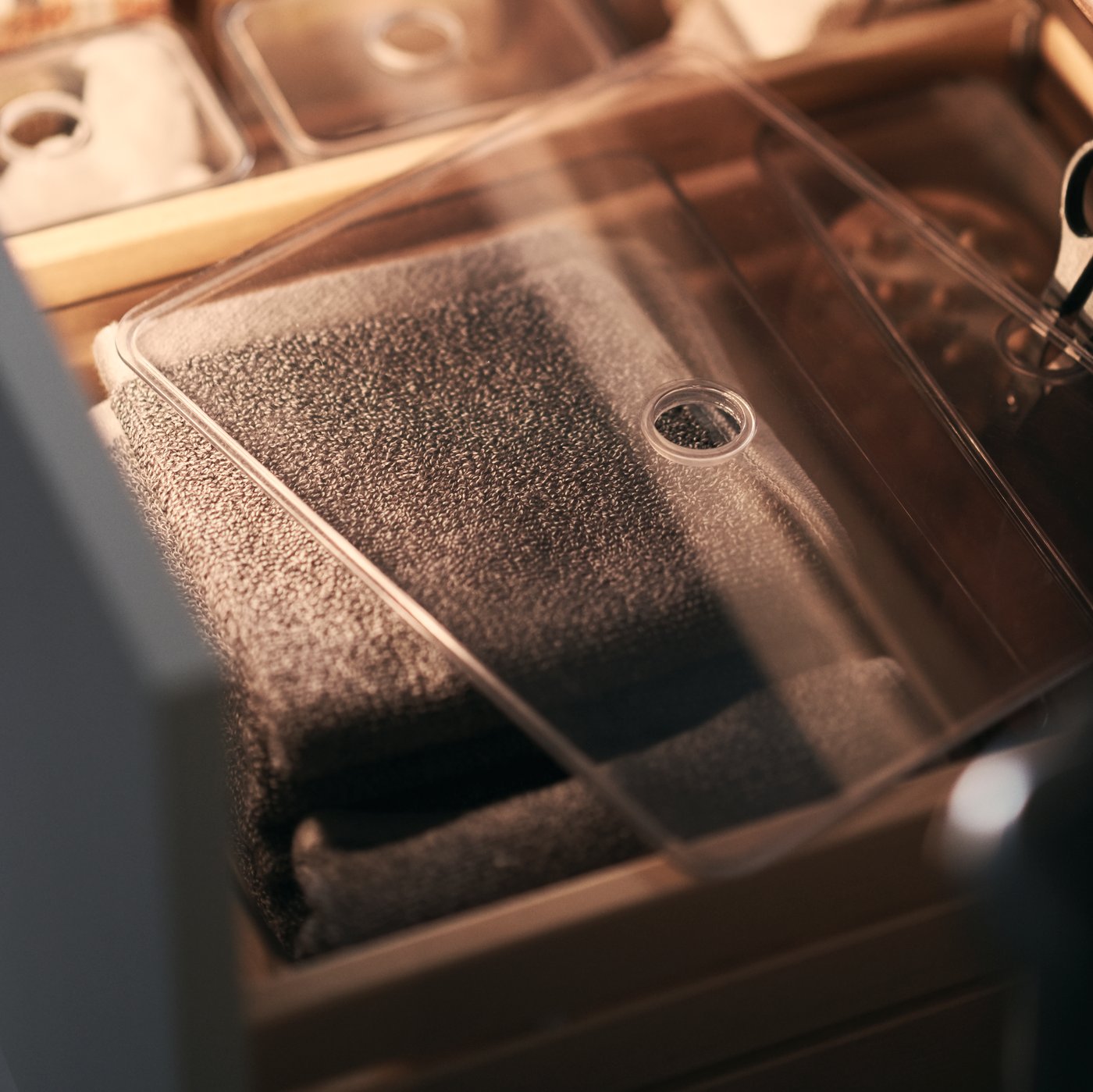 A GODMORGON contianer with a clear lid that is filled with bathroom accessories including face flannels.