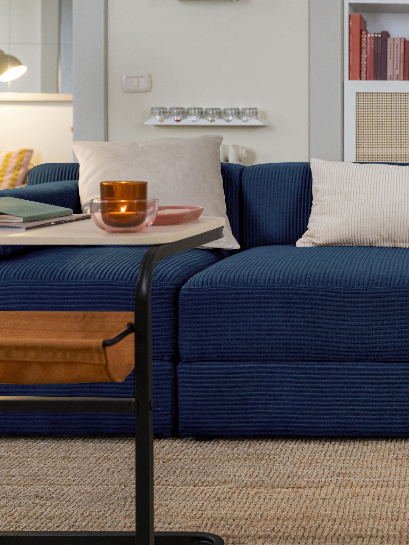 Soggiorno arredato con il divano modulare JÄTTEBO a 3 posti in tessuto blu scuro Samsala, con cuscini chiari e un tavolino accanto.