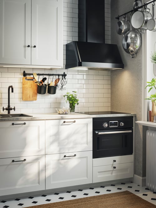 Multiple base cabinets outfitted with white AXSTAD drawer fronts and SKRUVHULT handles, a microwave and an extractor hood.