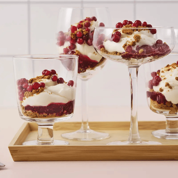 Cheesecake al pan di zenzero con confettura di mirtilli rossi poste in bicchieri di altezze diverse.