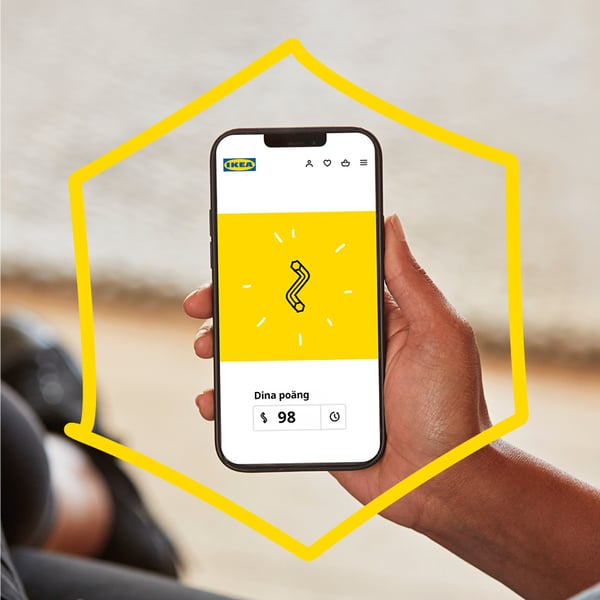 A hand holding a cellphone showing an Allen key symbolizing IKEA Family rewards.