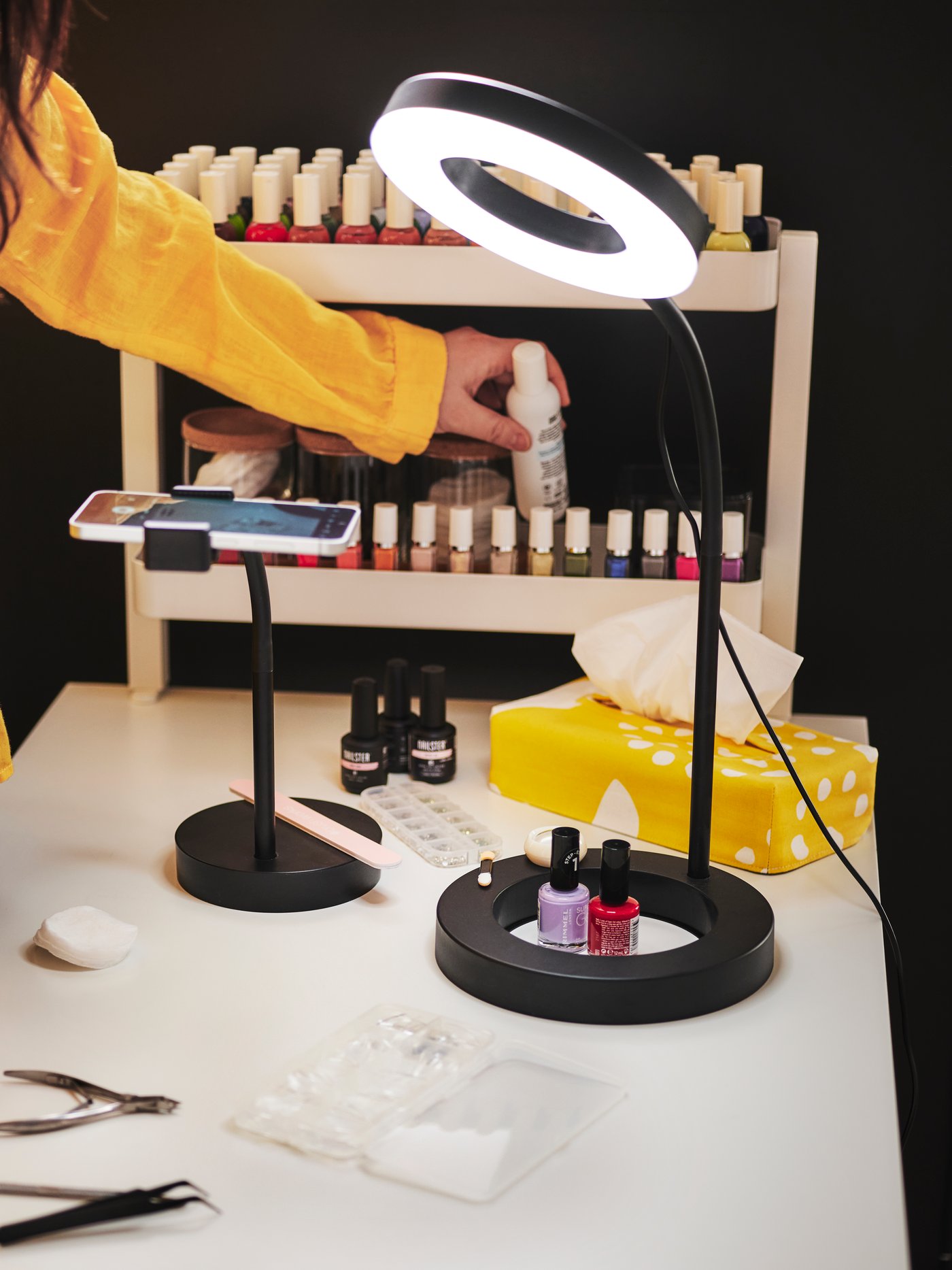 A person in a yellow shirt uses a LÅNESPELARE ring light with phone holder while working on nails at a well-lit table.