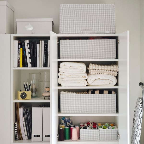 Ein übersichtlicher Kleiderschrank mit STUK-Accessoires, in denen Handtücher, Bücher und kleinere Bastelsachen in einem Regal untergebracht sind.