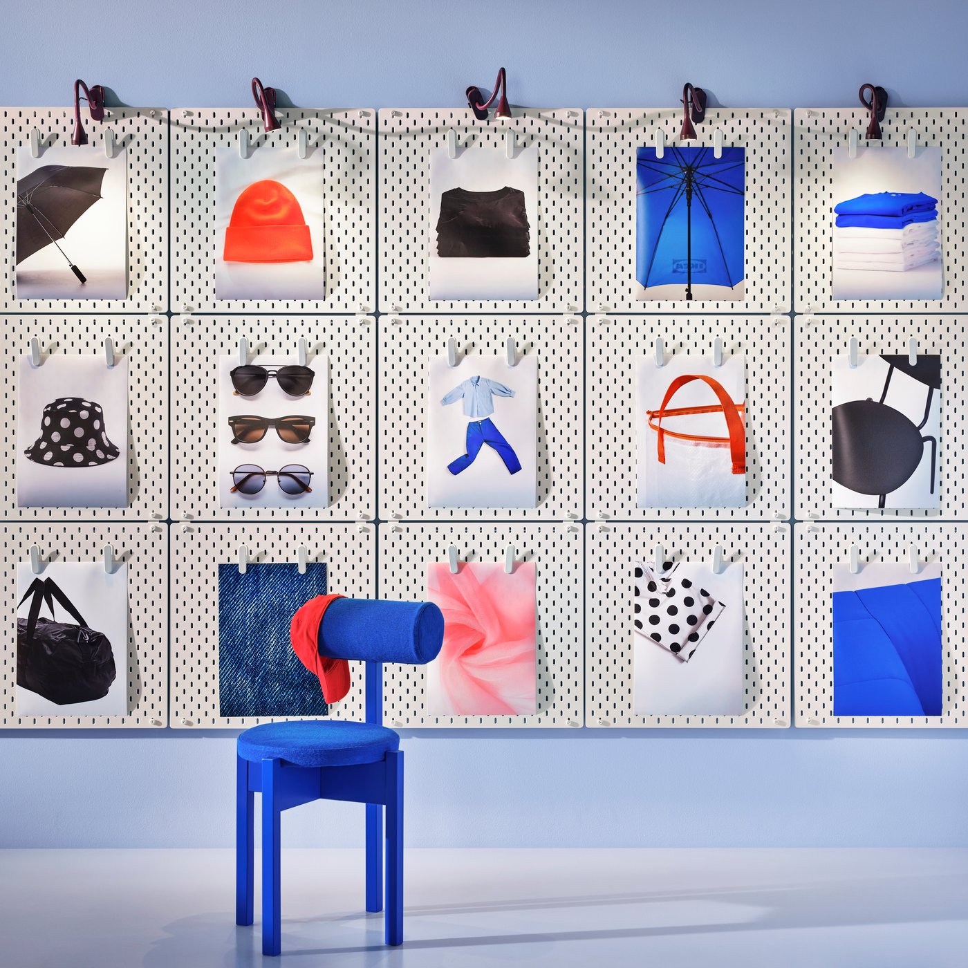 An IKEA PS 2026 chair stand in front of a whole wall of SKÅDIS pegboards holding colour prints of fashion items.