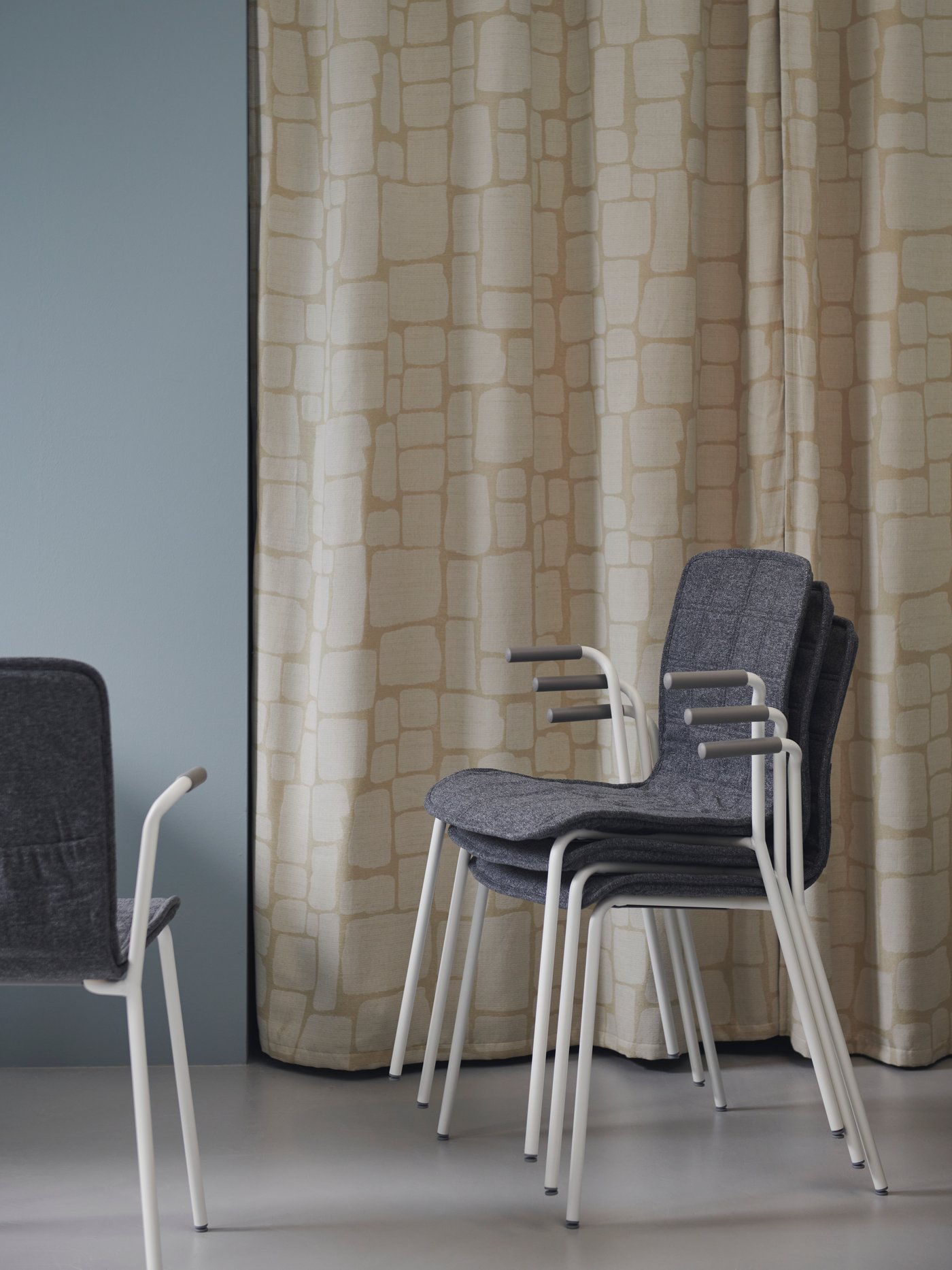 Three LÄKTARE conference chairs in light green/white are stacked in front of a beige curtain with patterns.