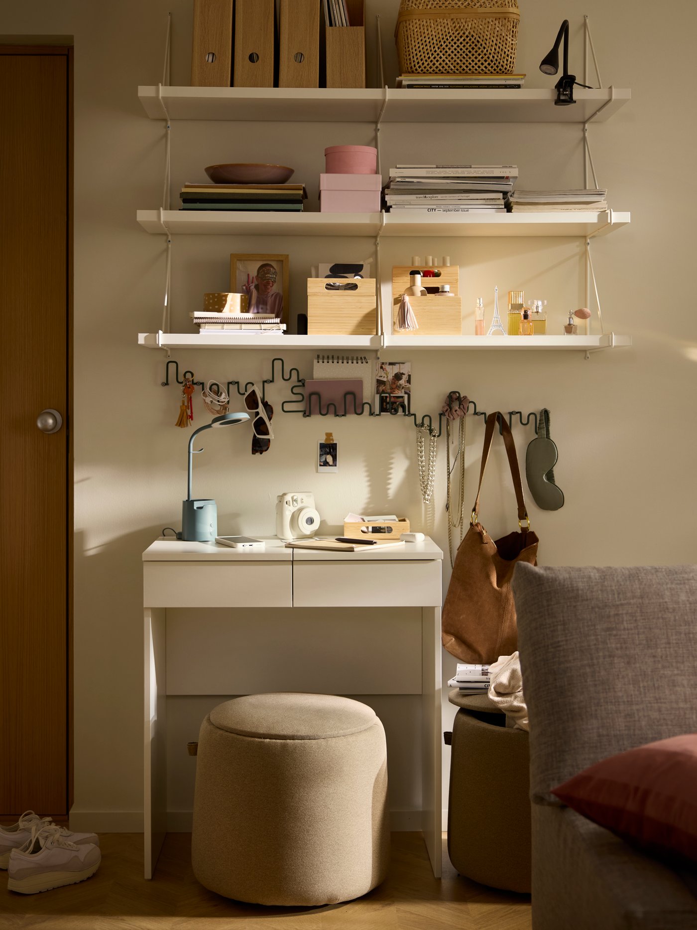 A white BRIMNES dressing table with white BERGSHULT/PERSHULT wall shelves above and a JÄRRESTAD pouffe as a stool beneath.